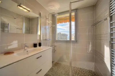 a kitchen with white cabinets and a large window at L'Edmond - 2min Plage - VCA in Cannes