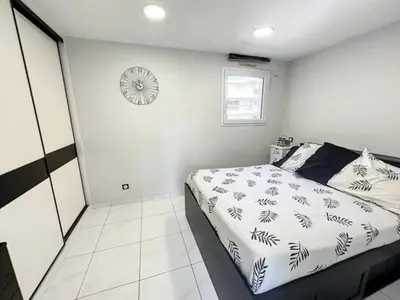 a bedroom with a bed and a clock on the wall at Superbe Appartement avec terrasse 2 chambres, 4 à 5 couchages piscine, à deux pas des plages et de la Croisette in Cannes