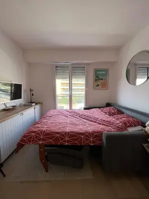 a bedroom with a bed with a red comforter at Studio lumineux à 2 mn à pied de la plage in Cannes