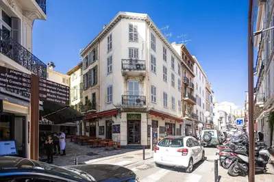 a tall white building on a city street with parked cars at Triplex 150m2 coeur vieille ville in Cannes