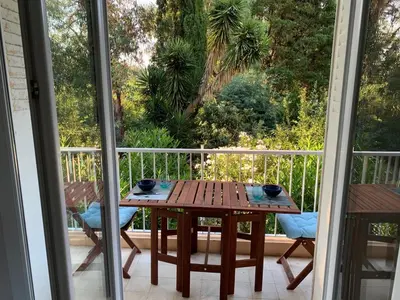 a wooden table sitting on a balcony with a table at Le jasmin du Riou in Cannes