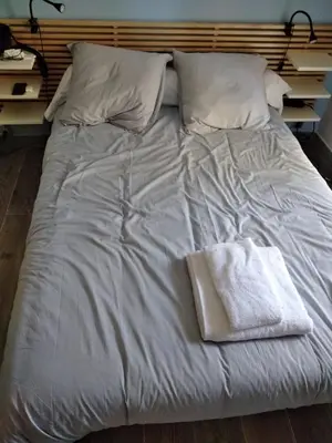 a white bed with two pillows and a towel on it at Le jasmin du Riou in Cannes