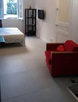 a living room with a red couch and a bed at Grand studio de 30m2 !central !spacieux !différent ! in Cannes