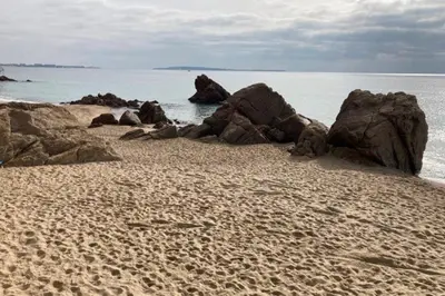 a sandy beach with some rocks in the water at Beautiful family cocoon of 65 m close to the sea in Cannes