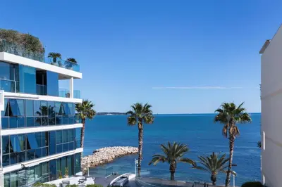 a view of a building and palm trees and the ocean at Apartment Lara Light apartment with an incredible view in Cannes