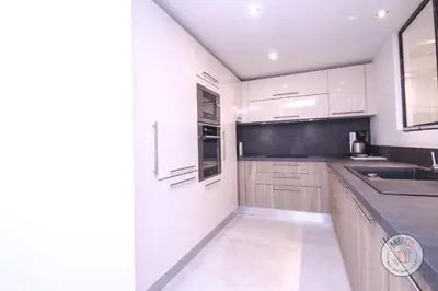 a kitchen with white cabinets and a black counter top at Appartement Céto Superb and luminous apartment in Cannes