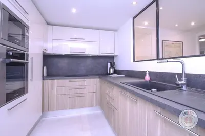 a kitchen with wooden cabinets and a sink at Appartement Céto Superb and luminous apartment in Cannes