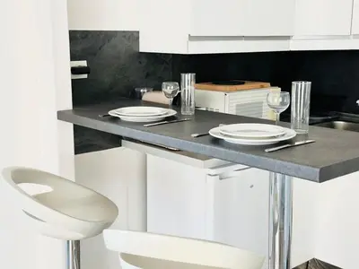 a kitchen with a table with plates and wine glasses at Palm Croisette - Studio vue Mer & Martinez in Cannes