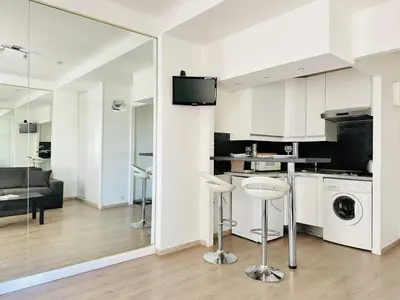 a kitchen with white cabinets and a living room at Palm Croisette - Studio vue Mer & Martinez in Cannes
