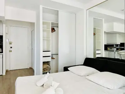 a white room with a bed and a black couch at Palm Croisette - Studio vue Mer & Martinez in Cannes