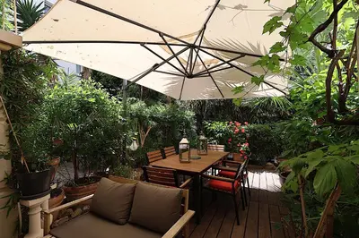 a wooden table with an umbrella in a garden at Appartement L'Etang Cannes Pointe Croisette in Cannes