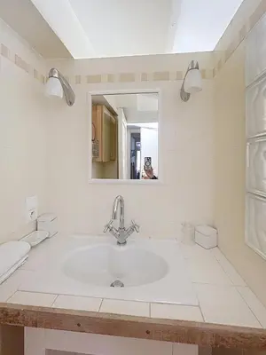a white bathroom with a sink and a mirror at Appartement L'Etang Cannes Pointe Croisette in Cannes
