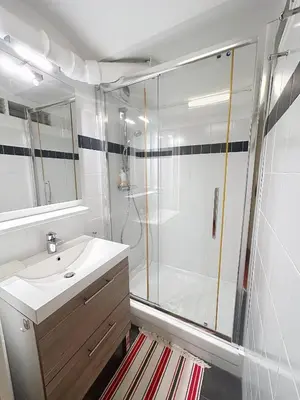 a white bathroom with a shower and a sink at Appartement L'Etang Cannes Pointe Croisette in Cannes