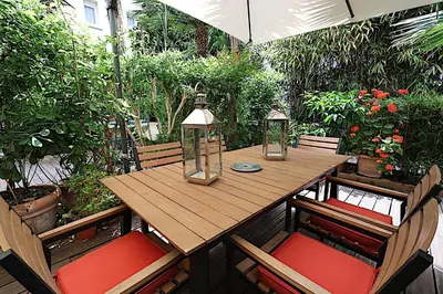 a wooden table and chairs on a patio with plants at Appartement L'Etang Cannes Pointe Croisette in Cannes