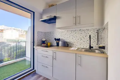 a kitchen with white cabinets and a large window at Magnifique studio avec terrasse au cœur de Cannes in Cannes