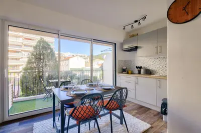 a kitchen with a table with chairs and a large window at Magnifique studio avec terrasse au cœur de Cannes in Cannes