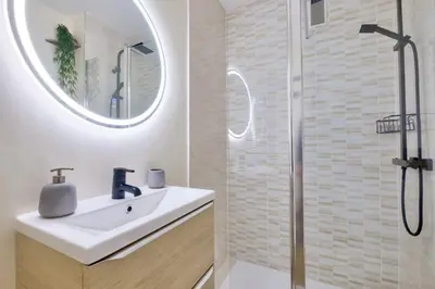 a white bathroom with a sink and a shower at Magnifique studio avec terrasse au cœur de Cannes in Cannes