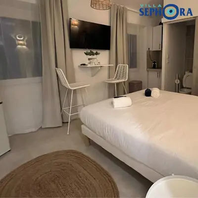 a bedroom with a bed and two chairs and a tv at VILLA SEPHORA CANNES in Cannes