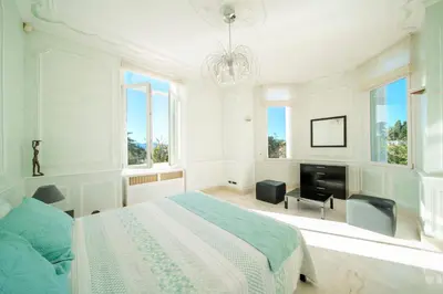 a white bedroom with a bed and a television at REF 1981 - Cannes Center - Particular town house for rent in Cannes