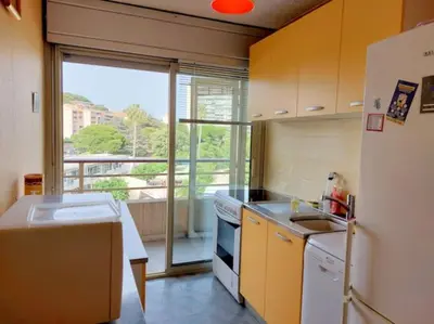 a kitchen with a white refrigerator and a window at Bocca Baie T2 en bord de mer - Axelle Loc Appart in Cannes