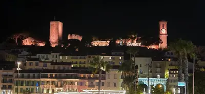 a city at night with a clock tower and buildings at Charmant studio in Cannes