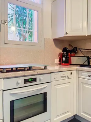 a kitchen with white cabinets and a window at Charmant studio in Cannes