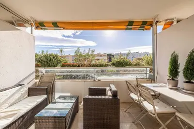 a balcony with a table and chairs and a large window at Charming apartment on Boulevard Alexandre III in Cannes