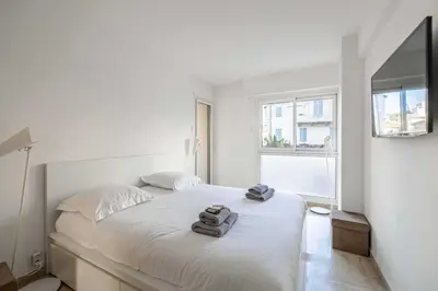 a white bedroom with a bed with two towels on it at Charming apartment on Boulevard Alexandre III in Cannes