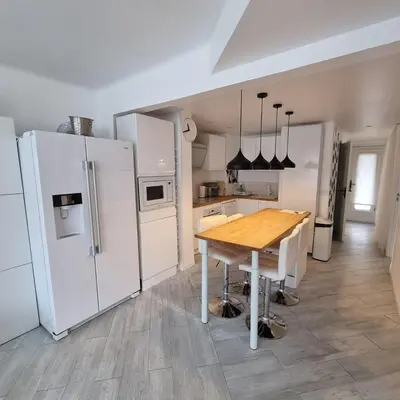 a kitchen with a wooden table and white appliances at Cannes Bliss - 12mn à pied du Palais, 5mn plages, clim, terrasse in Cannes