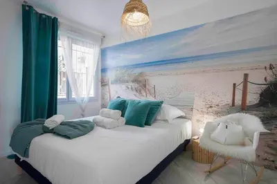 a bedroom with a bed with a painting of a beach at Cannes Bliss - 12mn à pied du Palais, 5mn plages, clim, terrasse in Cannes