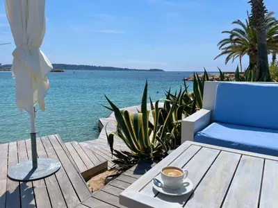a cup of coffee sitting on a table next to the water at Palm Beach apartment in Cannes