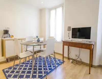 a room with a table and a desk and a tv at NEW Cannes Apt - Amazing Location - La Croisette in Cannes