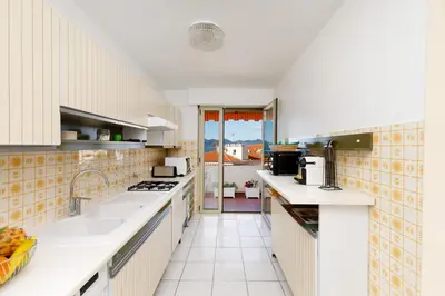 a large kitchen with white counter tops and a window at Gabriel YourHostHelper in Cannes