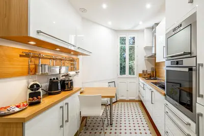 a kitchen with white cabinets and a wooden counter top at LE BOURGEOIS avec balcon, somptueux et lumineux, idéalement situé in Cannes