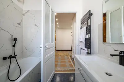 a white bathroom with a tub and a sink at LE BOURGEOIS avec balcon, somptueux et lumineux, idéalement situé in Cannes
