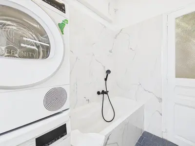 a white bathroom with a washer and dryer at LE BOURGEOIS avec balcon, somptueux et lumineux, idéalement situé in Cannes