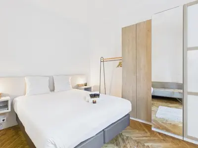 a bedroom with a large white bed and a mirror at LE BOURGEOIS avec balcon, somptueux et lumineux, idéalement situé in Cannes