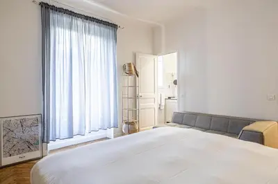 a white bedroom with a large bed and a window at LE BOURGEOIS avec balcon, somptueux et lumineux, idéalement situé in Cannes