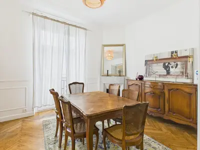 a dining room with a wooden table and chairs at LE BOURGEOIS avec balcon, somptueux et lumineux, idéalement situé in Cannes