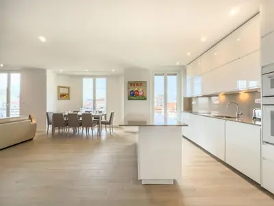 a kitchen with white cabinets and a dining room at Le Duplex by Winsome Destination in Cannes