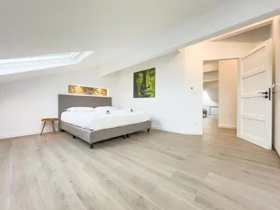 a white bedroom with a bed and a wooden floor at Le Duplex by Winsome Destination in Cannes