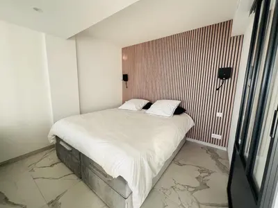a small bedroom with a bed with white sheets at Sea View Bellamare next Palais Festival in Cannes