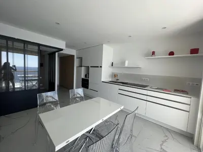 a white kitchen with a white table and chairs at Sea View Bellamare next Palais Festival in Cannes