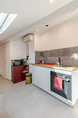 a large kitchen with white cabinets and a stove at Grand Studio Cannes - 5min Plages & Gare & Palais des Festivals - Climatisation in Cannes