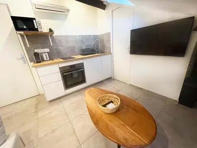 a small kitchen with a wooden table and a television at Petit Studio Cannes - 5min Plages & Gare & Palais des Festivals - Climatisation in Cannes