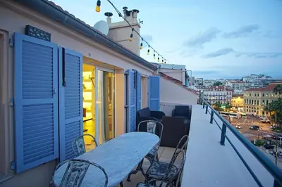 a balcony with blue shutters and a table and chairs at Facing old Port of Cannes Duplex WOW this view Olam Properties in Cannes