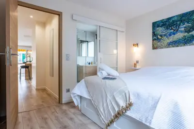 a white bedroom with a large bed and a bathroom at 2-room apartment with terrace close to the center in Cannes