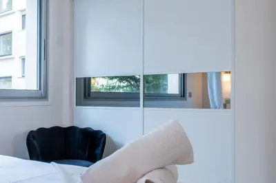 a bedroom with a bed and a chair and a mirror at 2-room apartment with terrace close to the center in Cannes