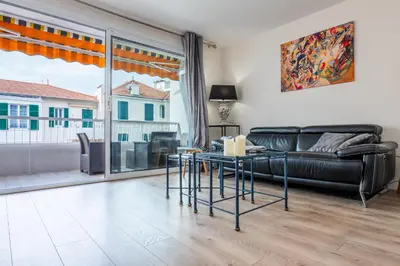 a living room with a black leather couch and a table at 2-room apartment with terrace close to the center in Cannes