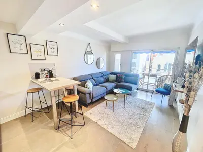 a living room with a blue couch and a table at 2 BR Croisette balcony & sea view Olam Properties in Cannes